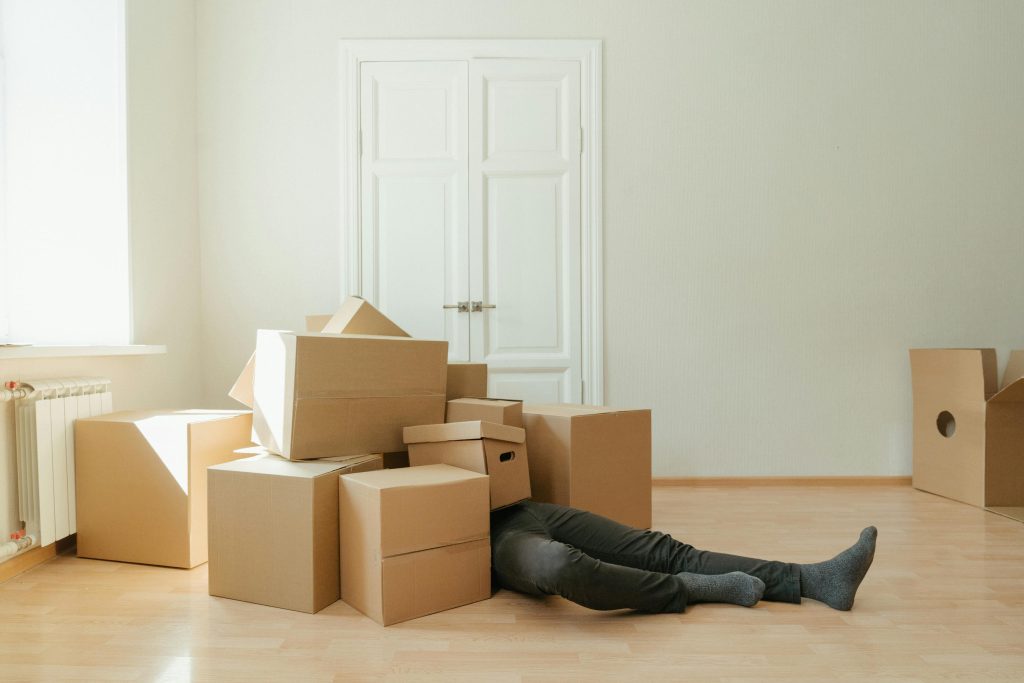 pexels photo 4553183 4553183 Person on floor surrounded by cardboard boxes during moving; concept of stress and relocation.